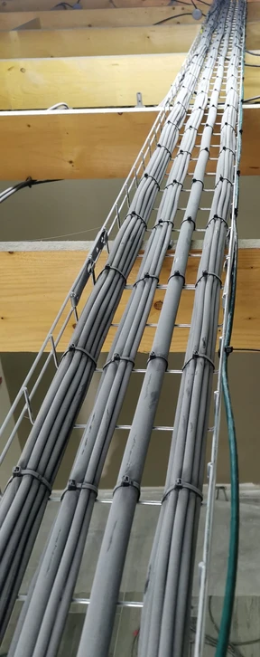 Électricien professionnel en chemise à carreaux travaillant sur installation électrique résidentielle, manipulant fils et connexions dans boîtier mural blanc