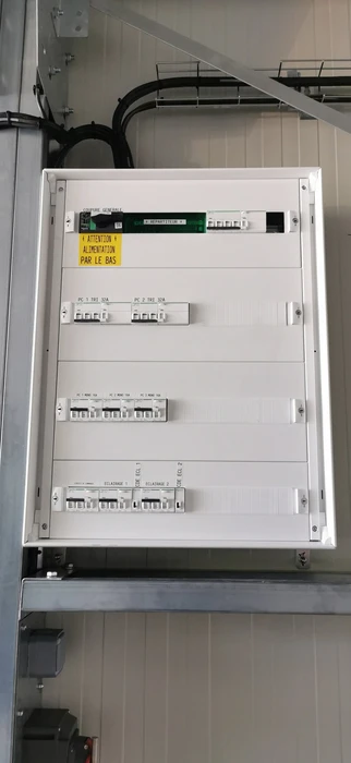 Intérieur résidentiel, main d'électricien tenant fil électrique bleu sortant d'une ouverture dans cloison placo