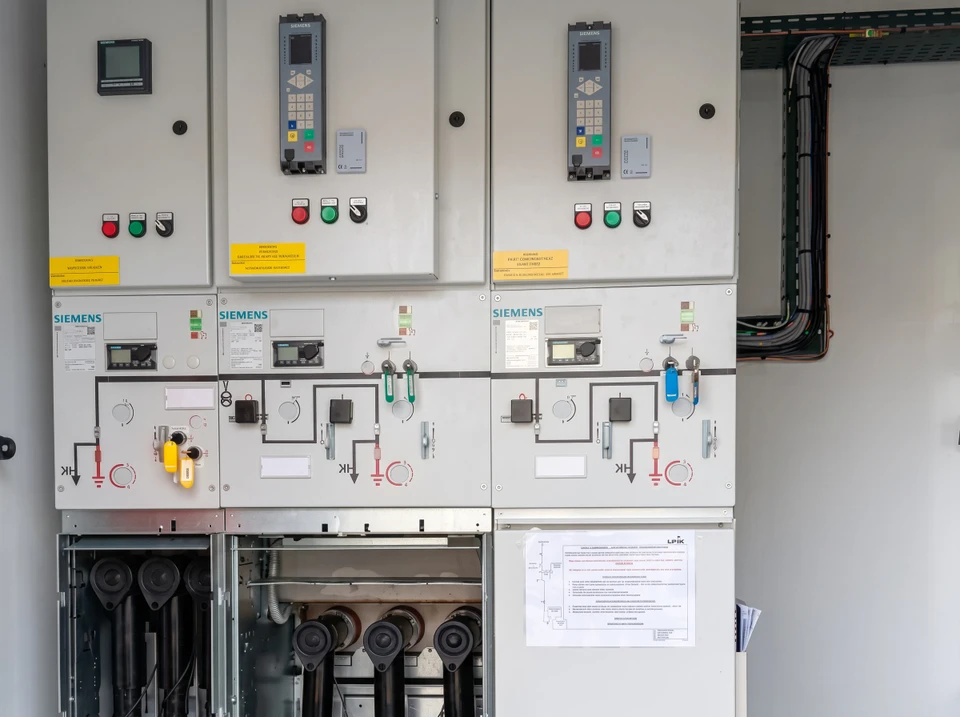 Salle électrique industrielle avec tableaux de commande muraux comportant voyants lumineux colorés, boutons d'arrêt d'urgence rouges et interrupteurs