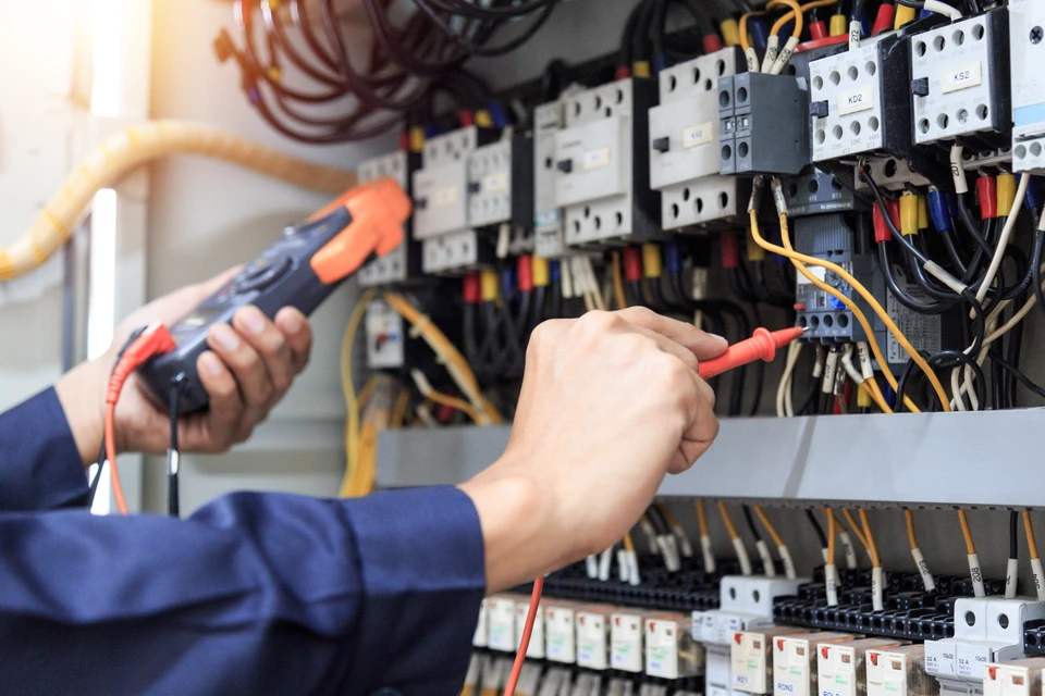 Un électricien effectue des mesures électriques dans un tableau de distribution intérieur