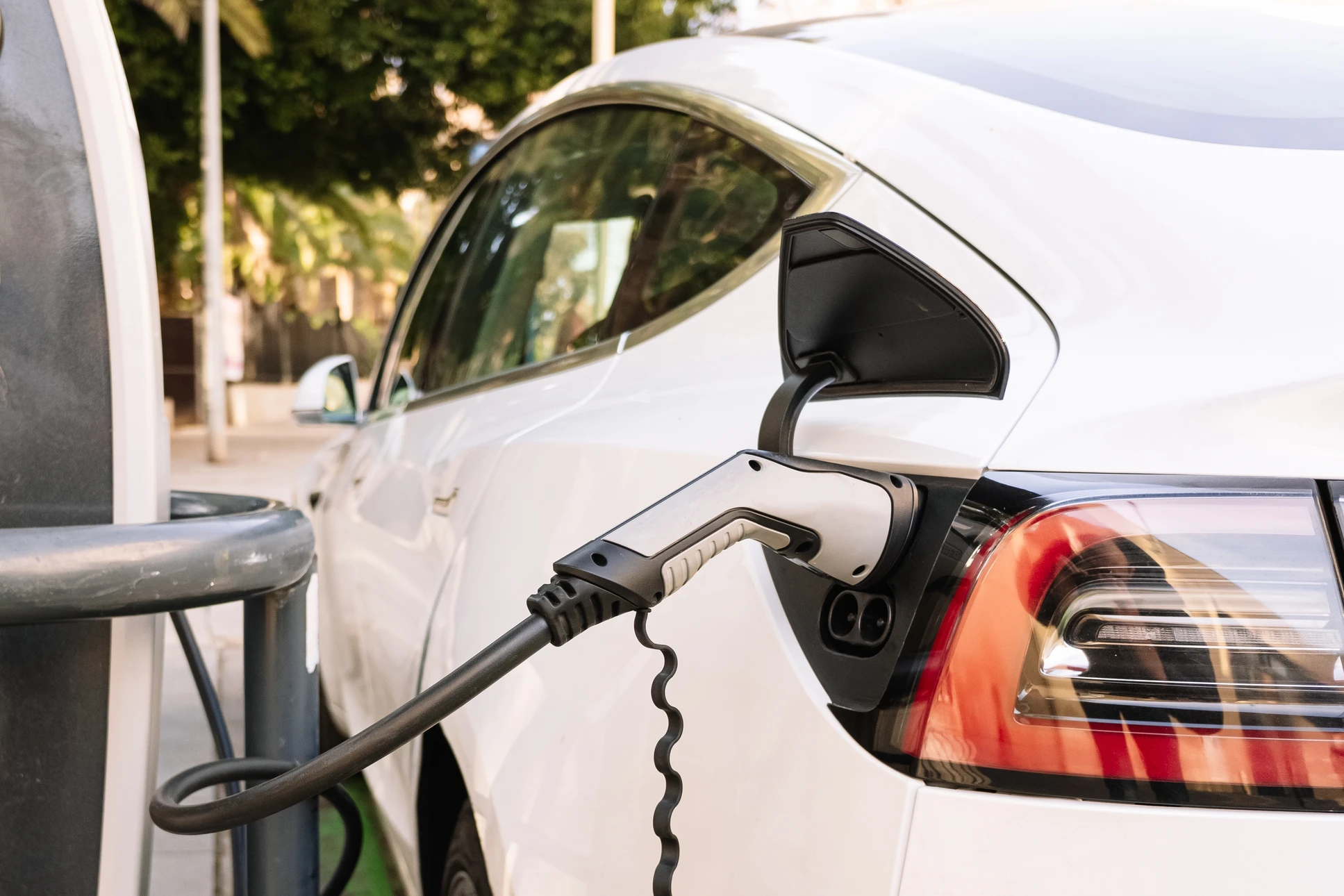 Femme branchant une voiture électrique à la borne de recharge